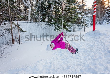 Little girl having fun outdoors in winter. Zipline for kids.