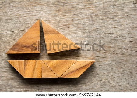 Tangram puzzle in sail boat shape on wooden background