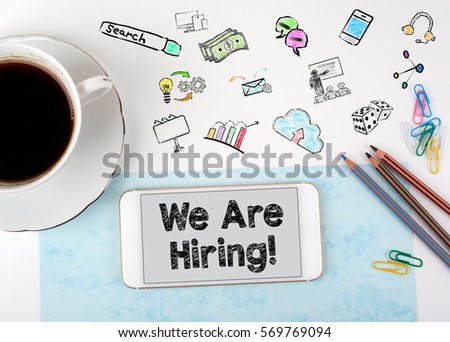 We are hiring. Mobile phone and coffee cup on a white office desk