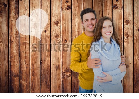 Portrait of smiling couple embracing against wooden planks