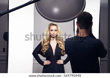 Photographer taking pictures of an attractive and beautiful model. Backstage shooting. Fashion, beauty, glamour concept.