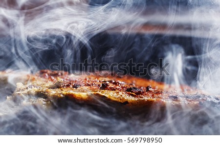 smoke and steam rise from a pork steak Royalty-Free Stock Photo #569798950