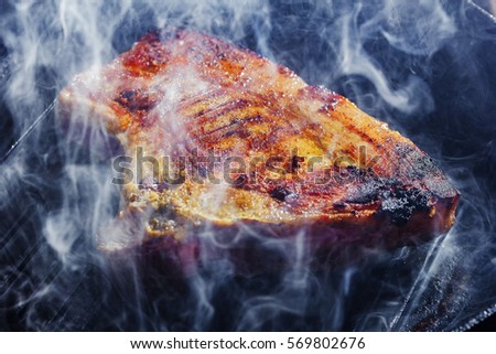 smoke and steam rise from a pork steak Royalty-Free Stock Photo #569802676