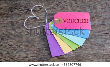 word VOUCHER on colorful of gift tag on wooden table