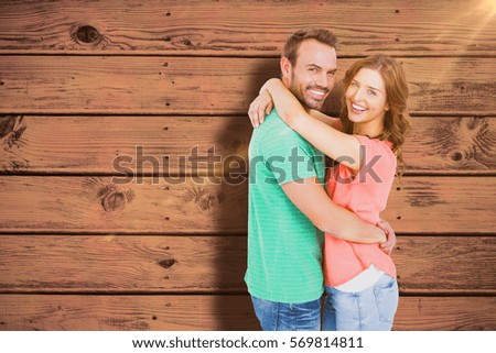 Happy young couple cuddling against blue paint splashed surface