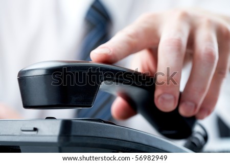 Male hand holding phone receiver over telephone Royalty-Free Stock Photo #56982949