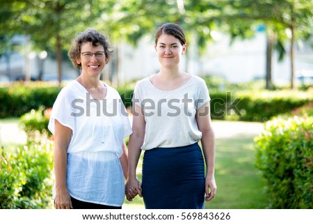 Smiling mother and daughter standing holding hands