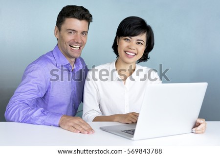 Laughing female manager and businessman at laptop