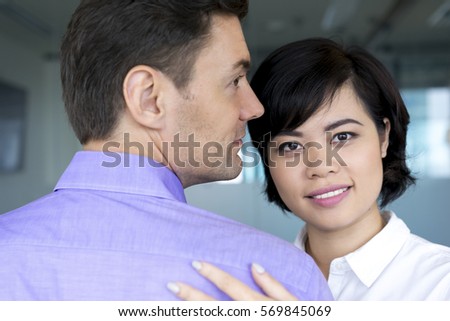 Happy Asian businesswoman embracing male colleague