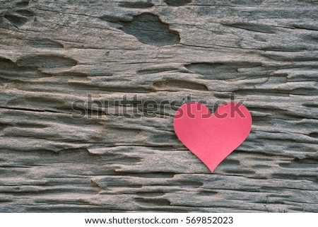 Red blank paper note with heart shape on grunge wooden background