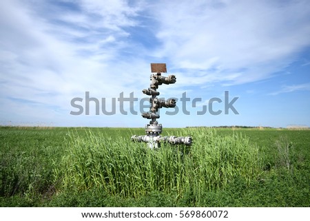 Canned oil well against the sky and field. Equipment of an oil well. Shutoff valves and service equipment.