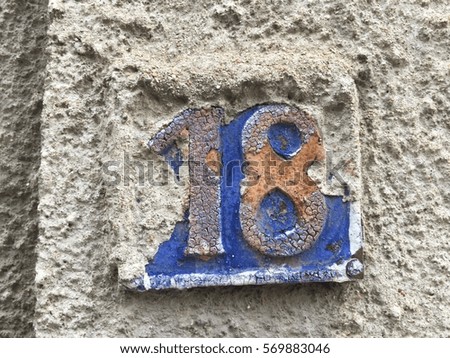 Vintage grunge square metal rusty plate of number of street address with number 18 closeup