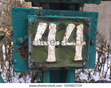 Vintage grunge square metal rusty plate of number of street address with number 44 closeup