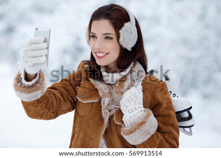 beautiful young woman with ice skates. Take a photo.