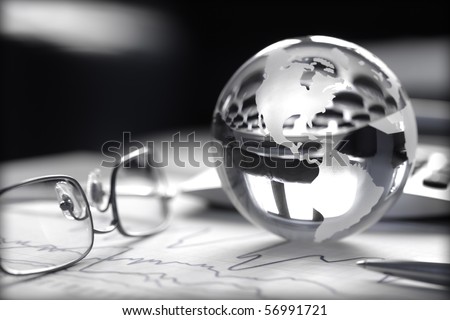 Toned image of glass globe with stock charts, calculator and spectacles