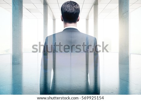 Back view of businessman in concrete room with bright daylight. Success concept. Double exposure
