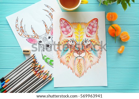 Colouring pictures and pencils on wooden table