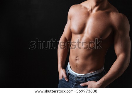 Cropped picture of attractive young african sportsman posing over black background.