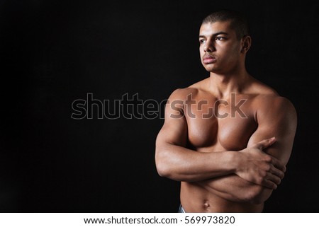 Picture of thoughtful young african sportsman posing over black background and looking aside.