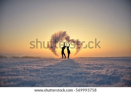 Young man and woman in love make fun in cold winter morning with hot water who freezes in the cold air. Valentine photo with space for your montage