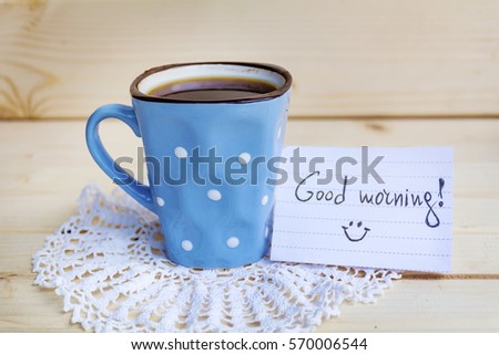 blue coffee mug with white dots  and notes good morning on a wooden background