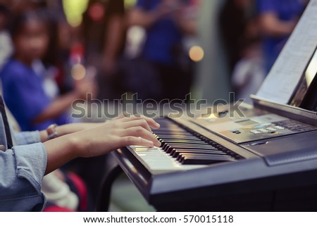 Girl hands playing on keyboard with music sheets.Dark tone.Selective focus.