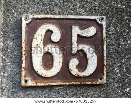 Vintage grunge square metal rusty plate of number of street address with number  65 closeup
