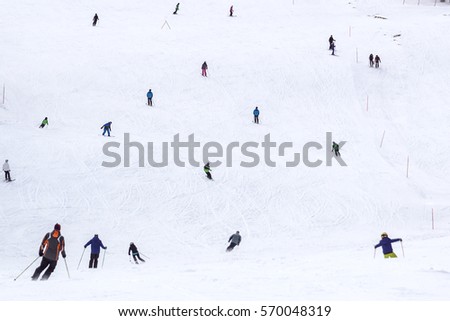 Skiers and snowboarders riding on a ski slope in Sochi mountain resort  snowy winter background