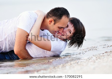 happy couple lying in the water hug. wet enjoying each other and kissing and laughter