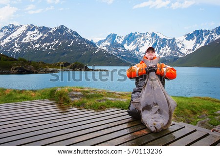 Man fisherman with a big fish Halibut. Behind the beautiful landscape. Norway