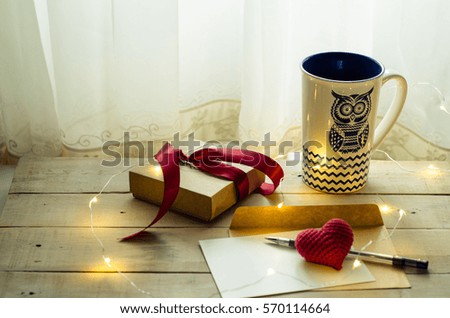 Romantic interior with gift box, heart and postcard with fairy lights Royalty-Free Stock Photo #570114664