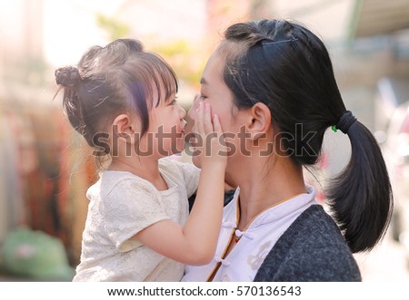 Happy loving family, mother and child girl kissing.