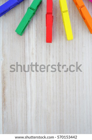 Top view of colorful wooden clothing pegs on bright Pine wood texture with free space.