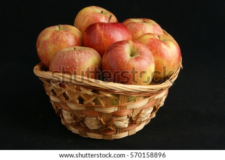 Seven red apples in a small basket on a black background