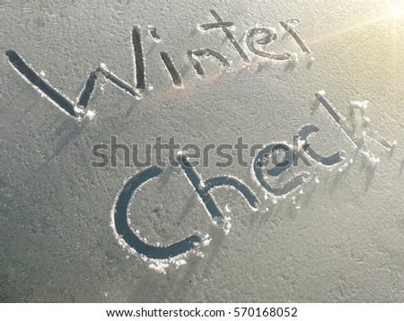 Winter Check drawn on a car windshield covered with fresh snow and ice
