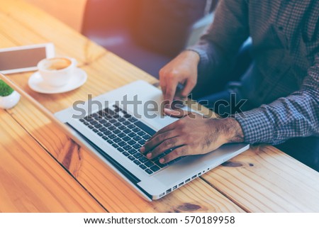 Hand of businessman using his laptop with a cup of coffee in coffee cafe. Portrait of business man using laptop in coffee shop. 