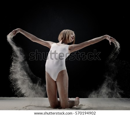 Little cute girl dancing with white powder on black background