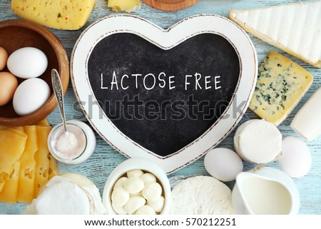 Allergic food concept. Dairy products and heart shaped board with text LACTOSE FREE on table Royalty-Free Stock Photo #570212251