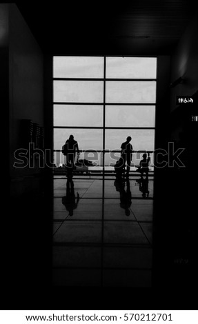 Silhouetted traveler and workers in Kuching International Airport, Malaysia. (Black and white)