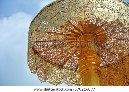 Golden elaborate umbrella in temple with blue sky background