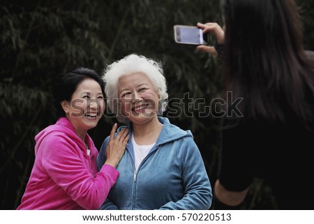Two older women smiling while having their photo taken