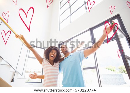 Red Hearts against excited young couple in their new home