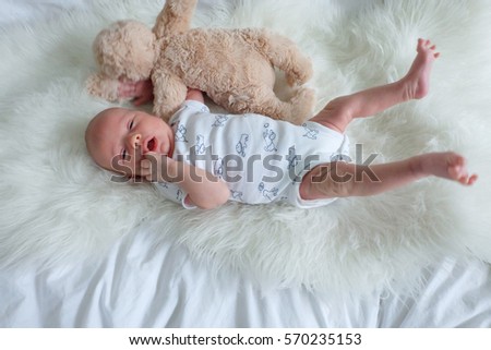 Baby playing on white fur with stuffed animal