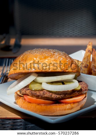 Hamburger with beef meat vegetable and fried potatoes on table in restaurant
