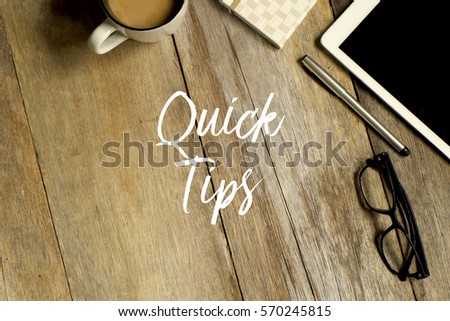 Business concept. Top view of tablet, glasses. notebook pen and a cup of coffee with QUICK TIPS written on wooden background.