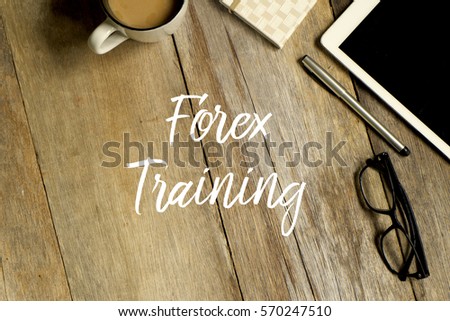 Business concept. Top view of tablet, glasses. notebook pen and a cup of coffee with FOREX TRAINING written on wooden background.
