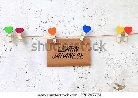 Business concept - words on paper writing LEARN JAPANESE  with wooden clamps on rustic wooden background.