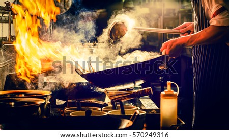 Chef is stirring vegetables  in wok Royalty-Free Stock Photo #570249316