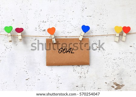 Business concept - words on paper writing GOAL with wooden clamps on rustic wooden background.
