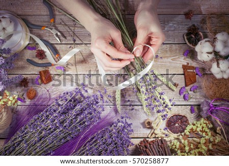 Hands of female florist arranging flower bouquet over a wooden table. Workplace of the florist. Vintage end retro toning. Top view